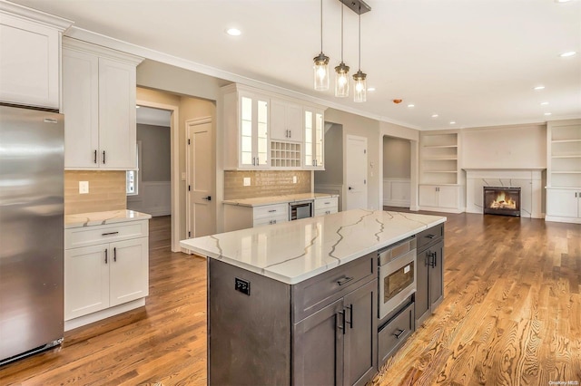 kitchen with white cabinets, hanging light fixtures, light wood-type flooring, and appliances with stainless steel finishes