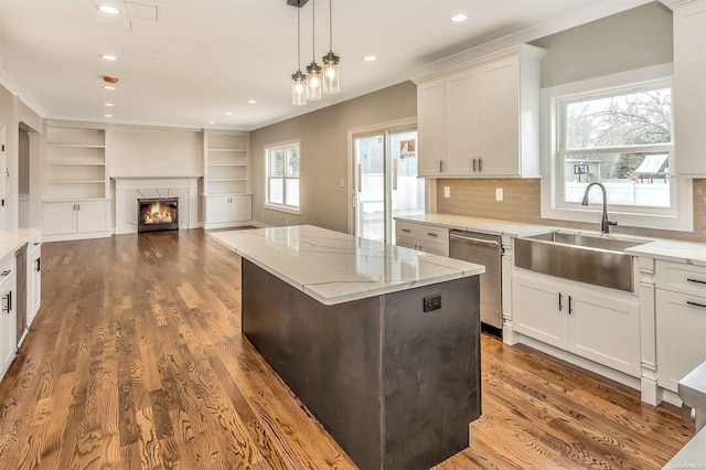 kitchen with dark wood-type flooring, sink, stainless steel dishwasher, tasteful backsplash, and a kitchen island