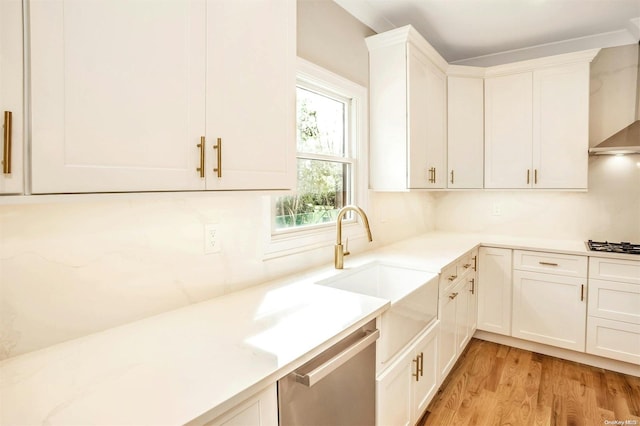 kitchen featuring sink, wall chimney exhaust hood, light hardwood / wood-style flooring, white cabinets, and appliances with stainless steel finishes