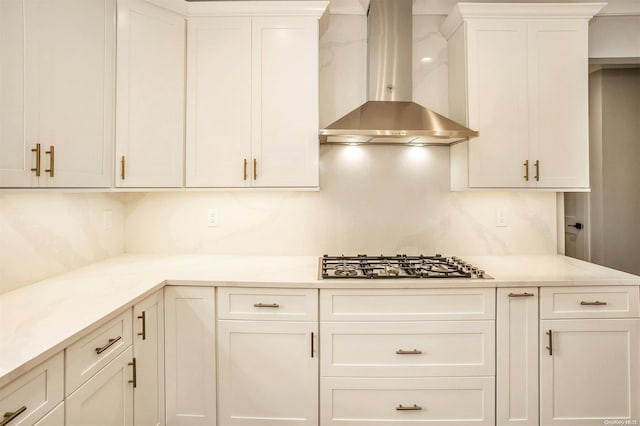 kitchen with backsplash, white cabinetry, stainless steel gas cooktop, and wall chimney exhaust hood