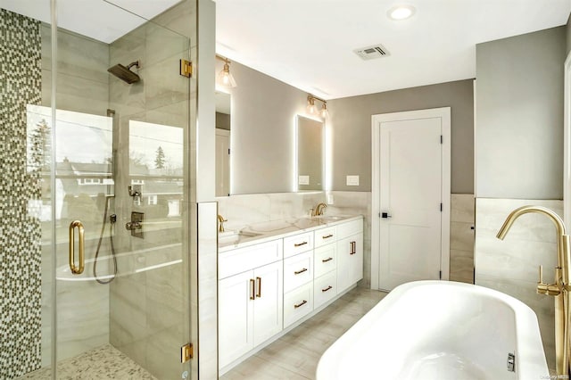 bathroom featuring vanity, independent shower and bath, and tile walls