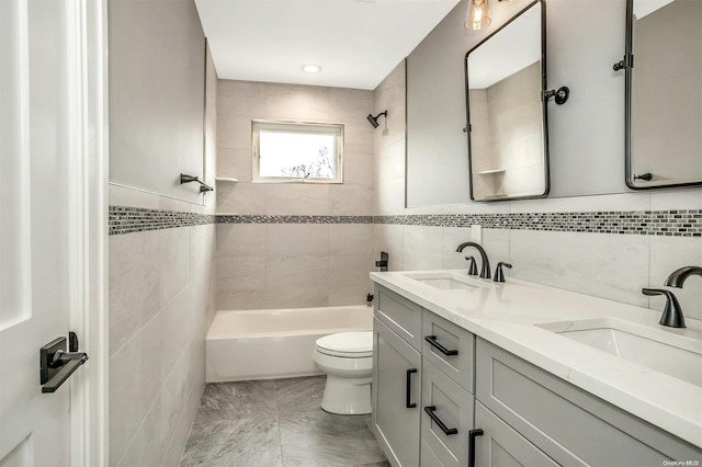 full bathroom with vanity, toilet, tile walls, and tiled shower / bath combo