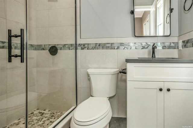 bathroom with vanity, toilet, a shower with door, and tile walls