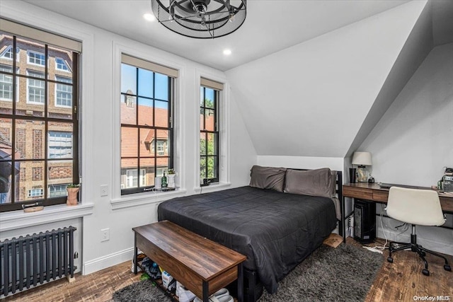 bedroom featuring hardwood / wood-style flooring, lofted ceiling, and radiator