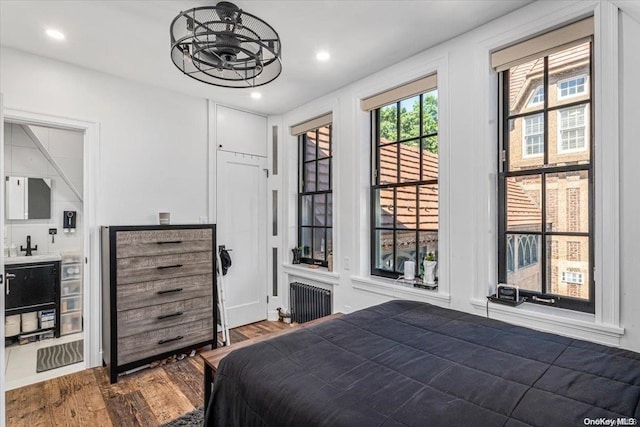 bedroom with access to exterior, wood-type flooring, and radiator heating unit