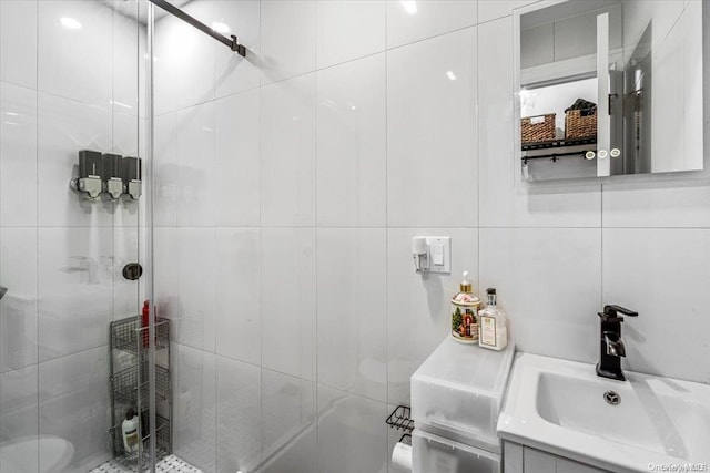 bathroom featuring a shower with door, vanity, and tile walls