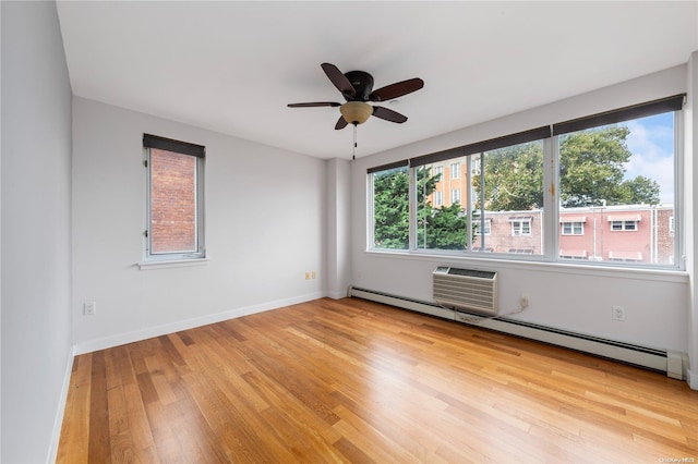 empty room featuring a healthy amount of sunlight, baseboard heating, and light hardwood / wood-style flooring