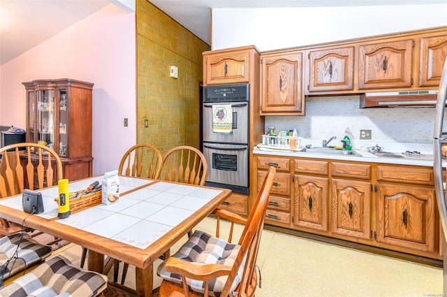 kitchen featuring white gas cooktop, lofted ceiling, exhaust hood, sink, and double oven