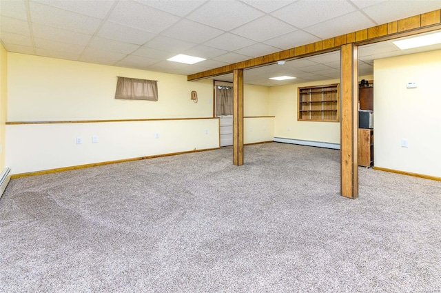 basement with baseboard heating, a paneled ceiling, and carpet flooring