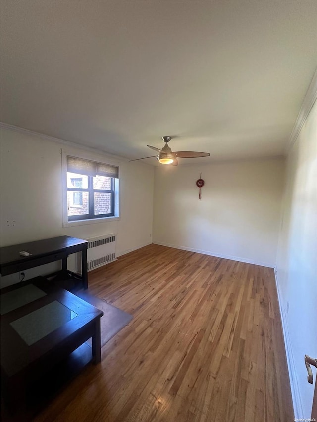 unfurnished living room with ceiling fan, hardwood / wood-style floors, crown molding, and radiator heating unit