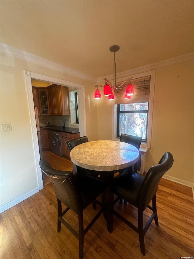 dining room with washer / dryer, crown molding, plenty of natural light, and light wood-type flooring