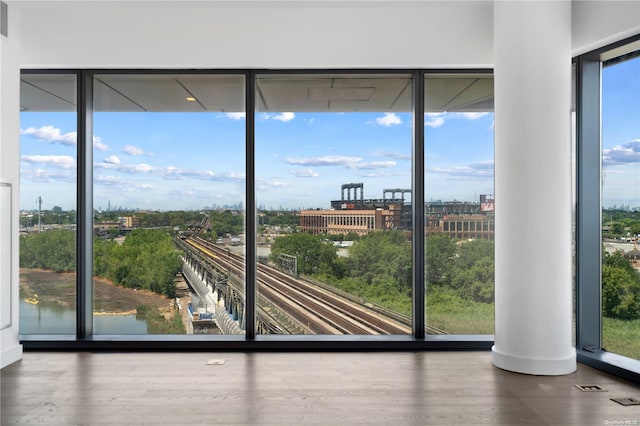 doorway to outside with expansive windows, plenty of natural light, a water view, and hardwood / wood-style floors