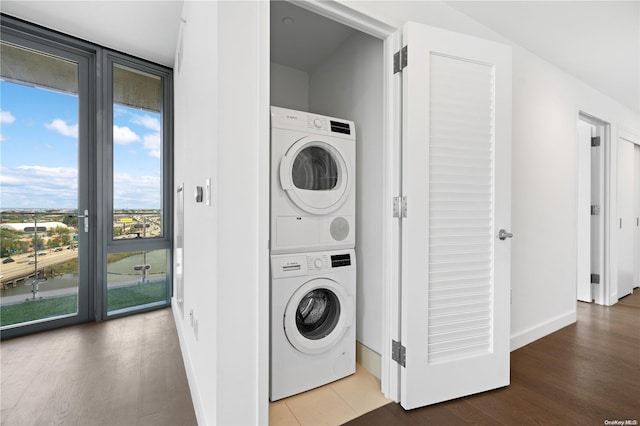 clothes washing area featuring wood-type flooring and stacked washing maching and dryer