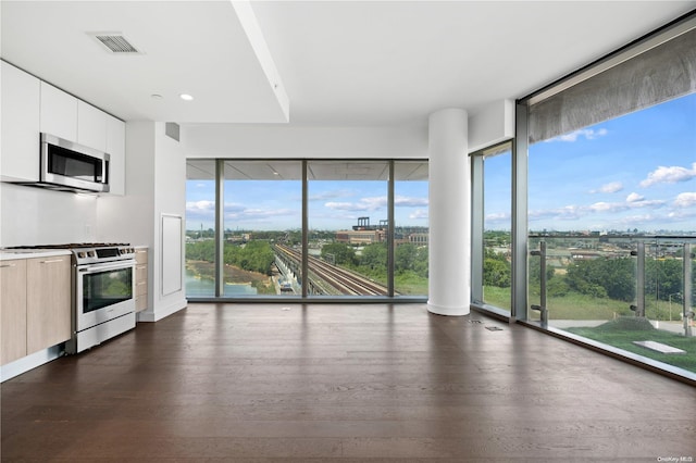 kitchen with stainless steel appliances, white cabinetry, and dark wood-type flooring