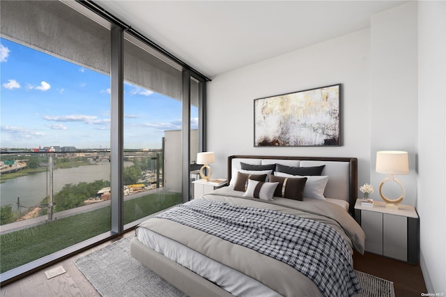 bedroom featuring access to outside, a water view, and hardwood / wood-style flooring