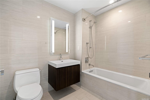 full bathroom featuring tile patterned flooring, toilet, vanity, tile walls, and tiled shower / bath