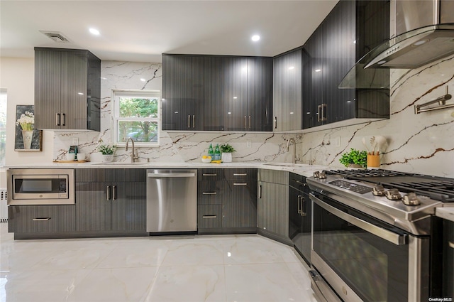 kitchen featuring wall chimney range hood, sink, appliances with stainless steel finishes, and tasteful backsplash