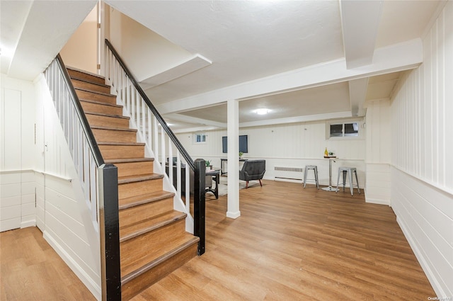 stairs featuring wood-type flooring and radiator heating unit