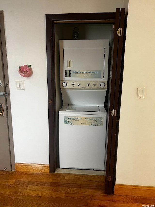 laundry area with wood-type flooring and stacked washing maching and dryer