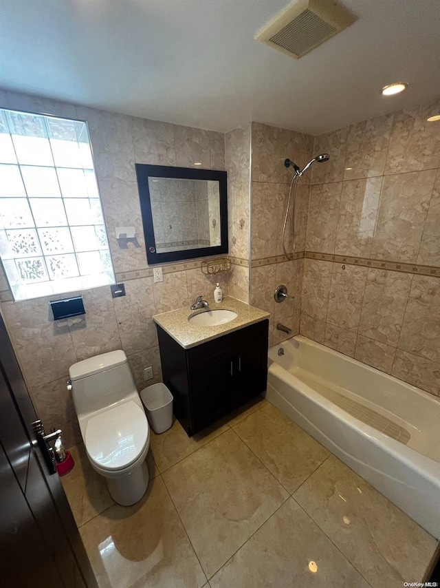 full bathroom featuring tiled shower / bath, vanity, toilet, and tile walls