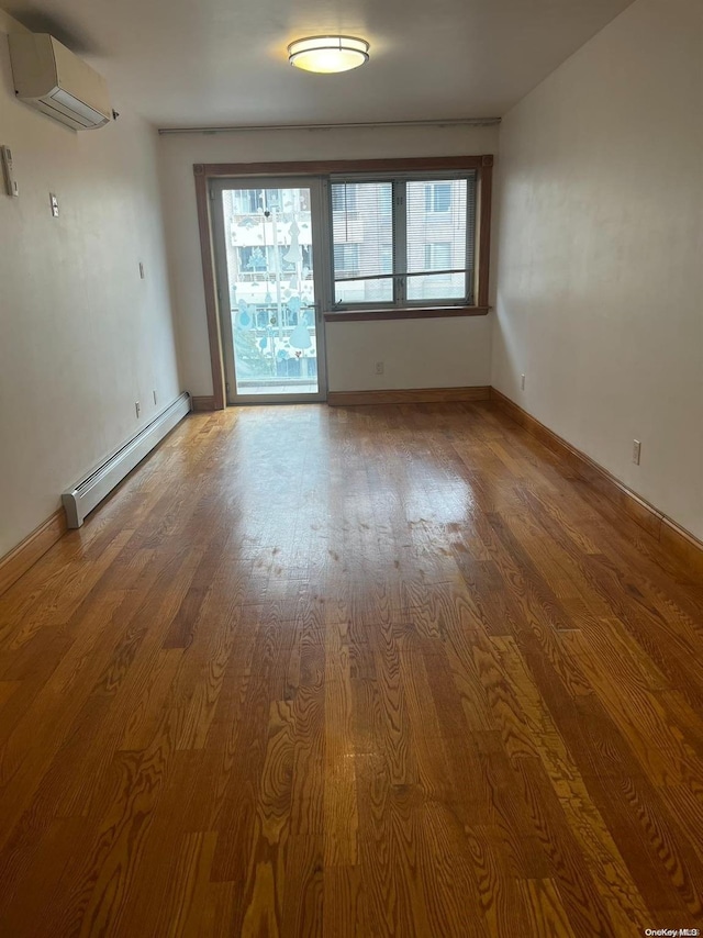 empty room with a baseboard radiator, a wall unit AC, hardwood / wood-style flooring, and a healthy amount of sunlight