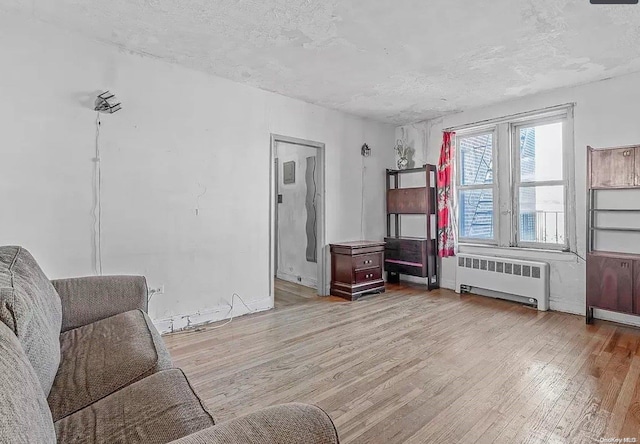 living area with radiator, a textured ceiling, and light wood-type flooring