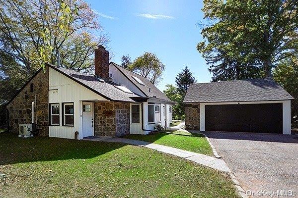 view of front of home featuring central air condition unit, a front yard, and a garage