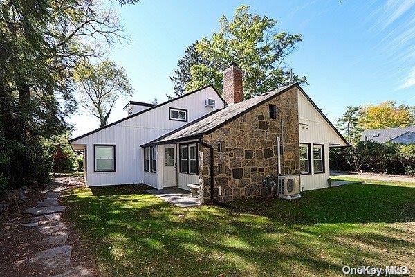 back of house with ac unit and a lawn