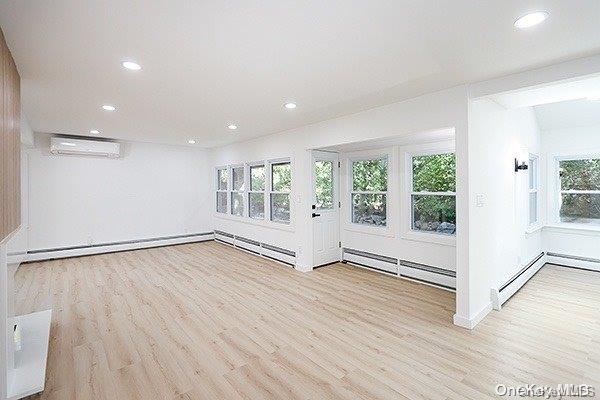 empty room featuring an AC wall unit and light hardwood / wood-style flooring