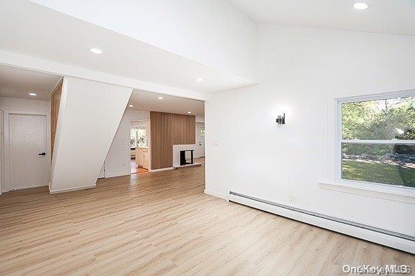 unfurnished living room featuring a baseboard radiator and light hardwood / wood-style flooring