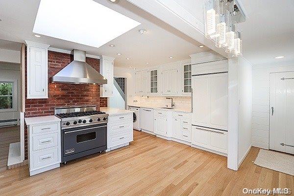 kitchen with white cabinetry, wall chimney exhaust hood, decorative backsplash, and high end range