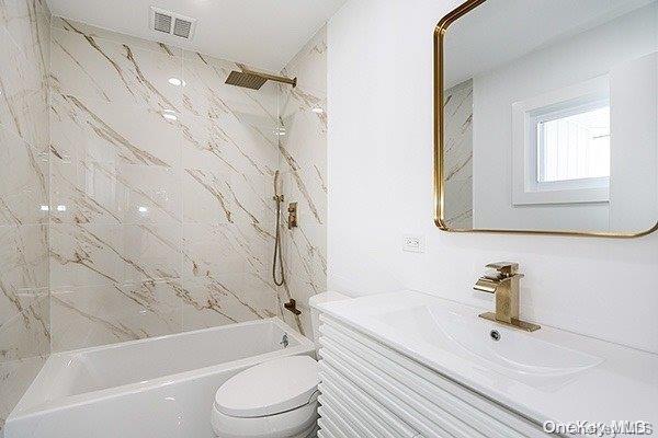 full bathroom featuring toilet, vanity, and tiled shower / bath combo