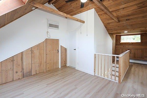 bonus room with vaulted ceiling with beams, light wood-type flooring, wooden ceiling, and wood walls