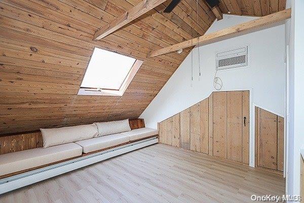 additional living space featuring beamed ceiling, light hardwood / wood-style floors, a skylight, high vaulted ceiling, and wood ceiling