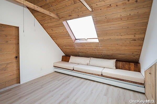 unfurnished room with light hardwood / wood-style floors, lofted ceiling with skylight, and wood ceiling