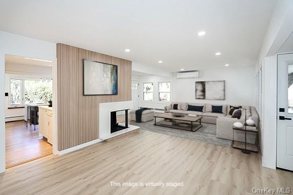 living room with baseboard heating, a wall mounted air conditioner, and light hardwood / wood-style flooring