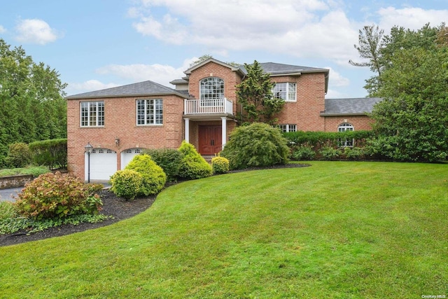 front of property featuring a balcony, a front yard, and a garage