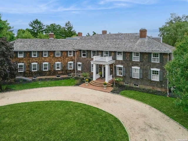 view of front of property featuring a balcony and a front lawn