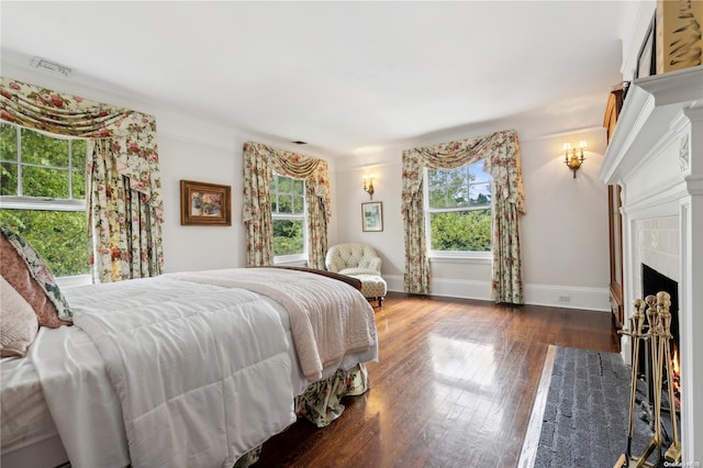 bedroom featuring dark wood-type flooring and a tiled fireplace