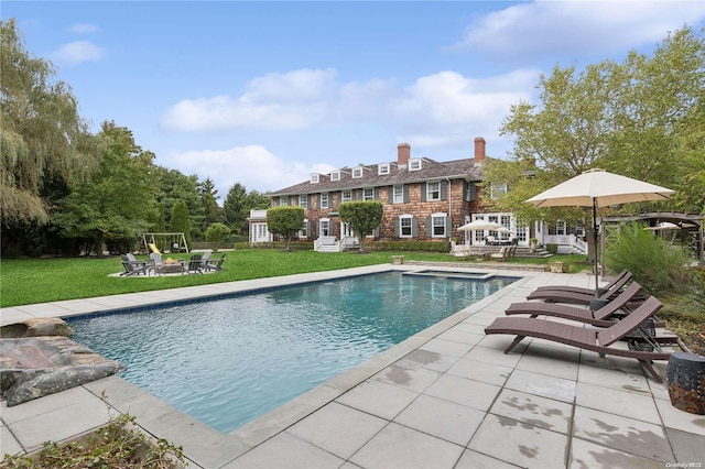 view of swimming pool featuring a lawn and a patio