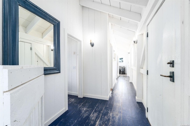 hallway with wooden walls, lofted ceiling with beams, and dark hardwood / wood-style floors