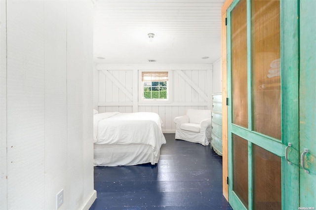 bedroom featuring dark hardwood / wood-style floors and wooden walls