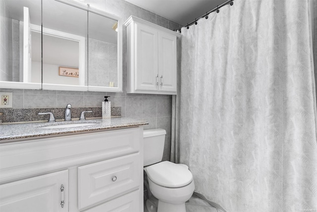 bathroom featuring vanity, toilet, and tile walls