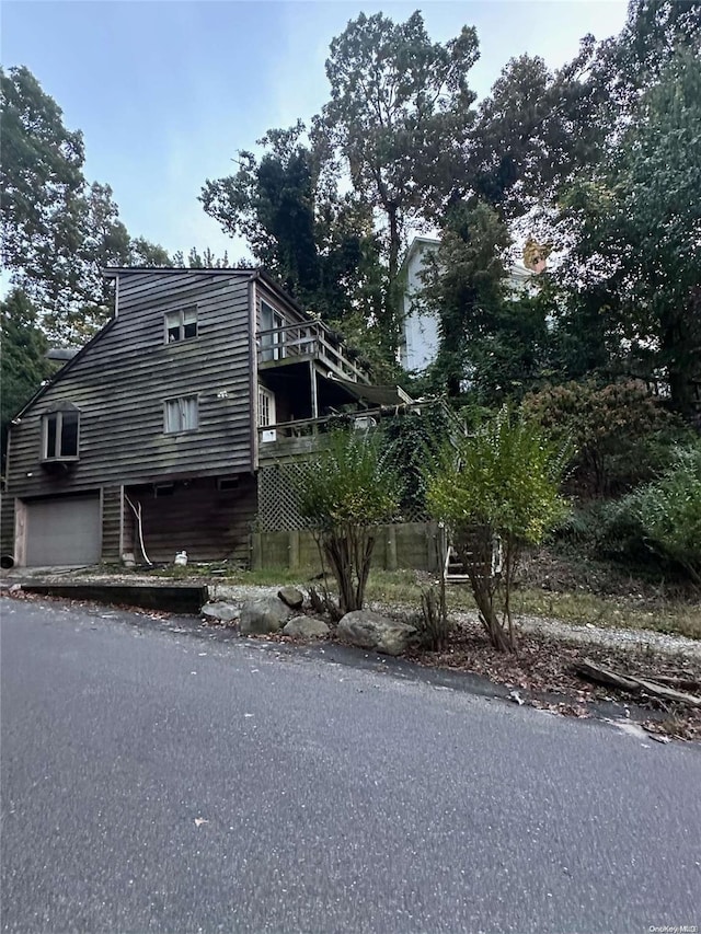 view of side of home featuring a garage and a wooden deck