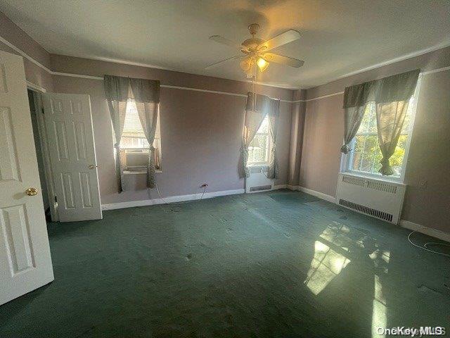 unfurnished room with ceiling fan, radiator heating unit, carpet floors, and plenty of natural light