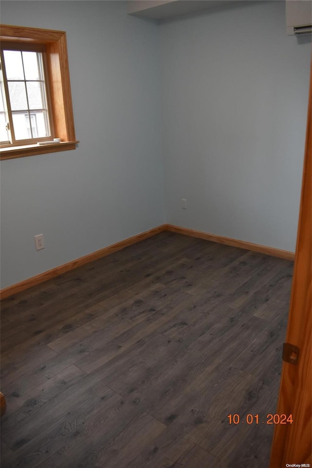 empty room with dark hardwood / wood-style flooring and a wall unit AC