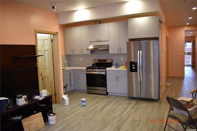 kitchen with tasteful backsplash, stainless steel appliances, extractor fan, light hardwood / wood-style flooring, and white cabinetry