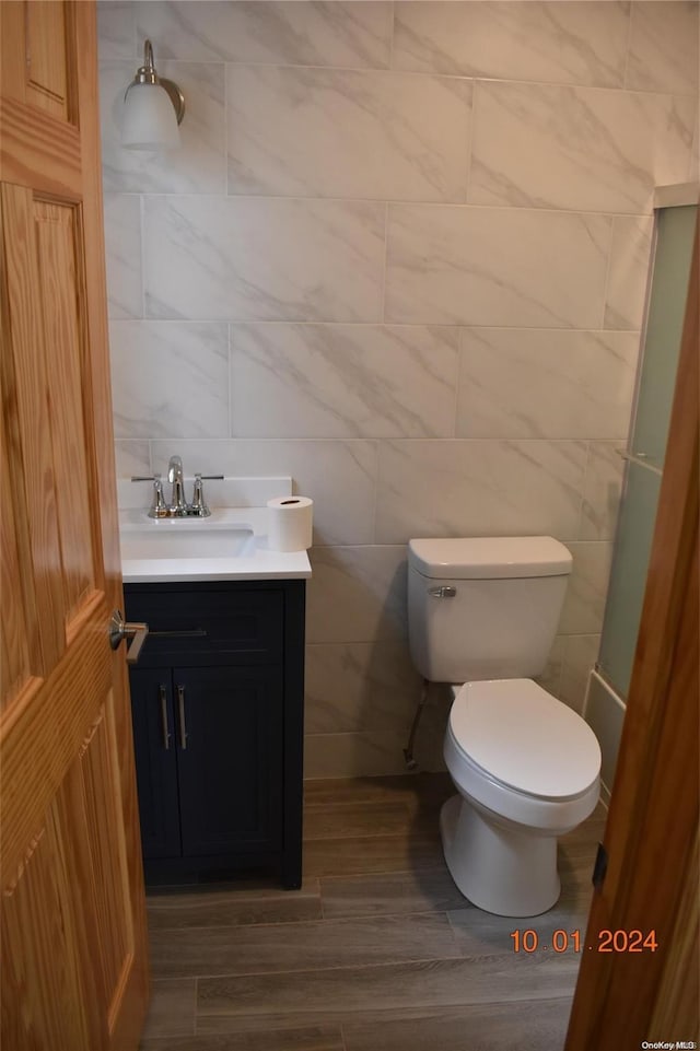 bathroom featuring hardwood / wood-style floors, vanity, tile walls, and toilet