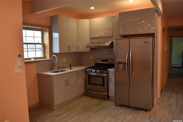 kitchen with white cabinetry, light wood-type flooring, wall chimney range hood, and stainless steel appliances