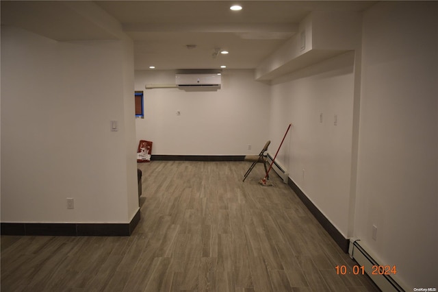 corridor featuring a wall unit AC, a baseboard radiator, and hardwood / wood-style flooring